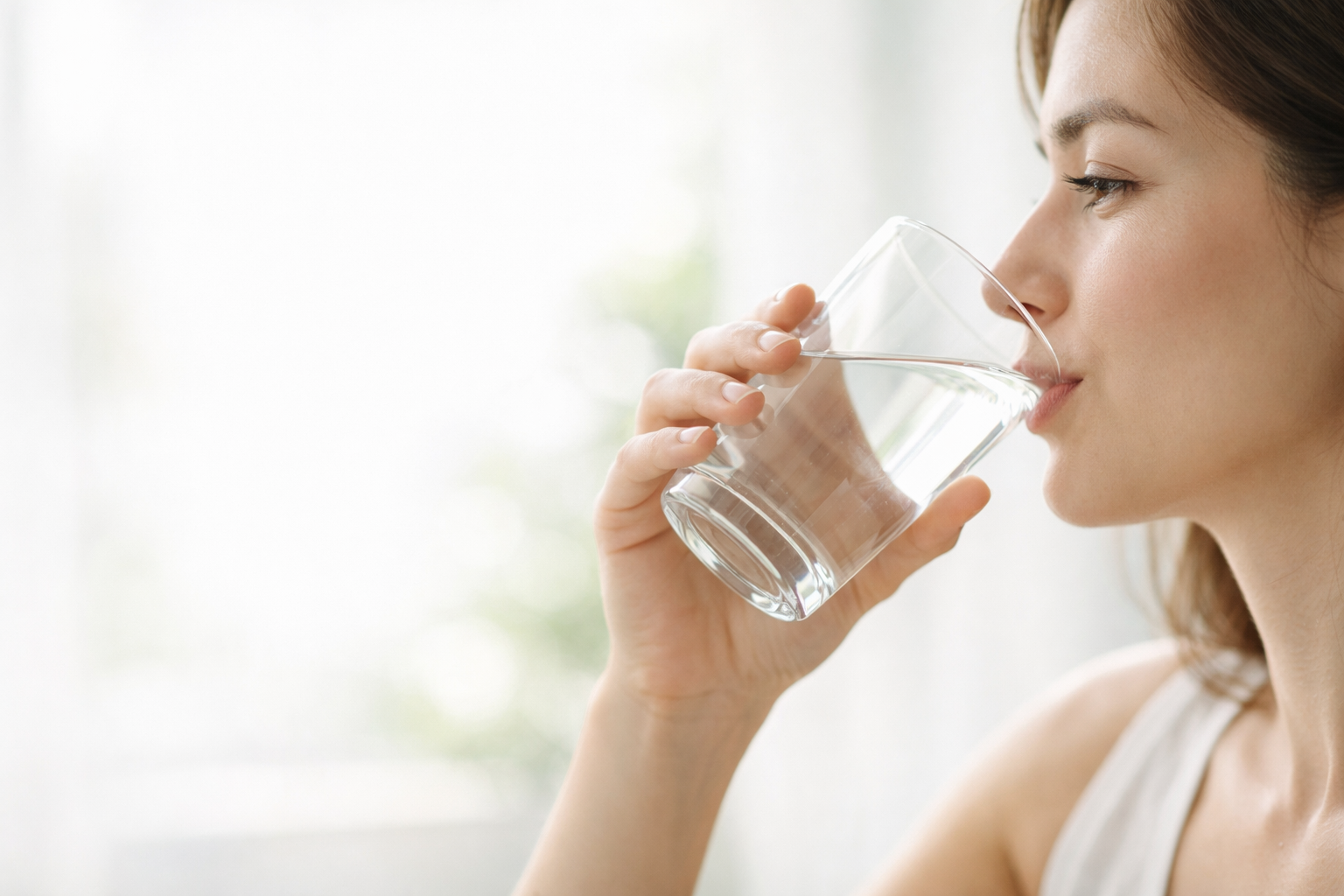 Woman drinking water from a glass with a blurred background